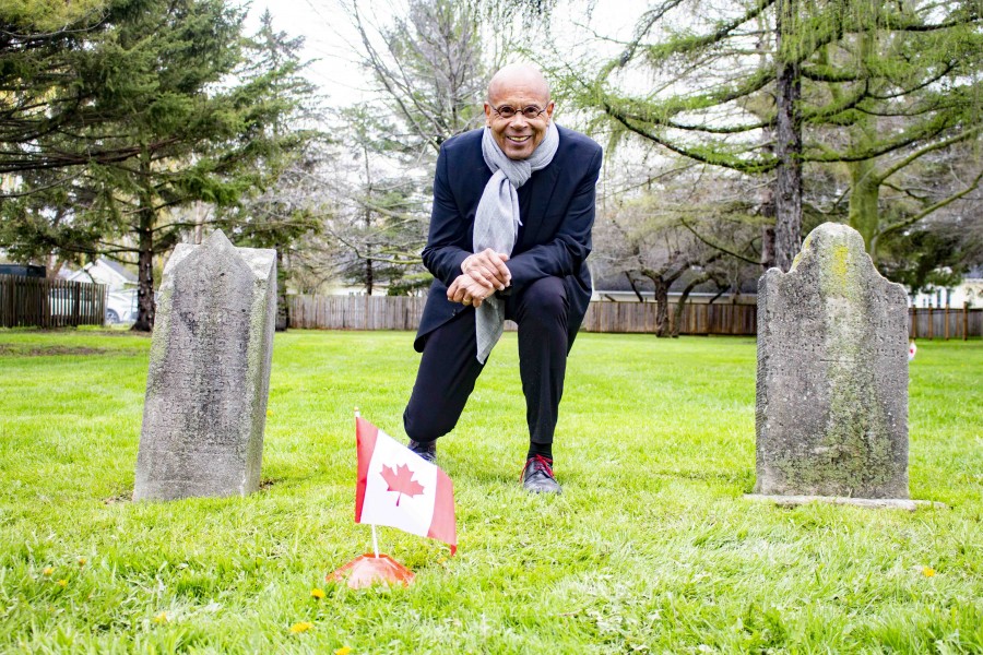 13 definitive soil anomalies were found by the technicians on Wednesday. Russell marked each one of them with a small Canadian flag. Here Russell kneels between two of the three remaining headstones, in front of what may be a new grave. (Evan Saunders)(Evan Saunders)