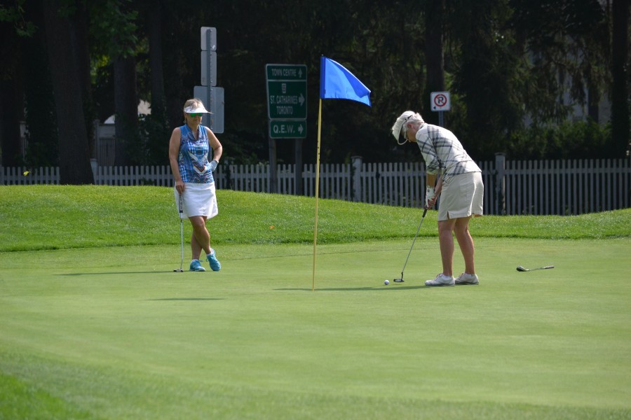 Ginny Green, who won the women's A flight, putts on #17. Yolanda Henry looks on. (Kevin MacLean/Niagara Now)