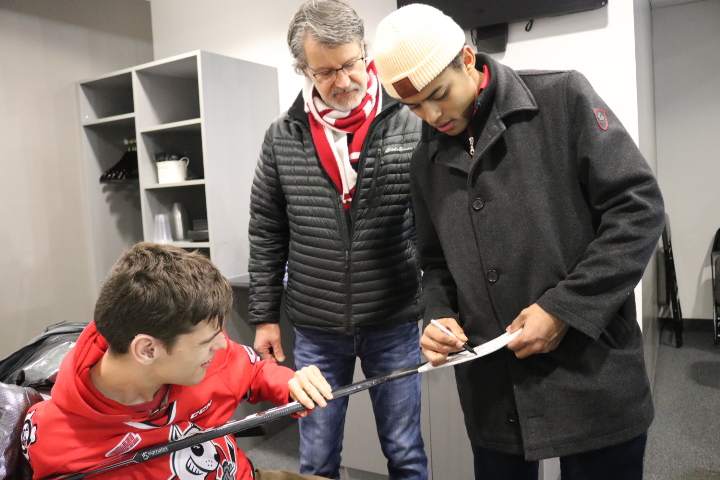 watch as Akil Thomas signs the stick he gave to Calvin after the WJC finals game. (Dariya Baiguzhiyeva/Niagara Now)
