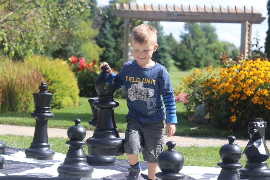 Felix Bator, 3, plays with chess at the party held at the library last Thursday. (Dariya Baiguzhiyeva/Niagara Now)