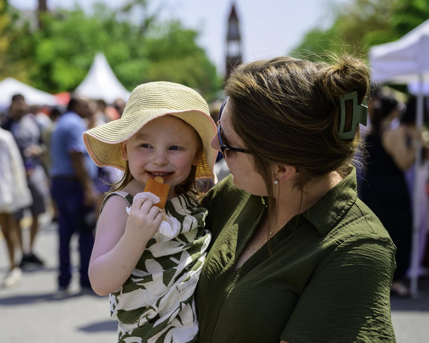 Three-year-old Addi Hughes is all smiles enjoying a peach popsicle, being held by her mother, Taylor Hughes.