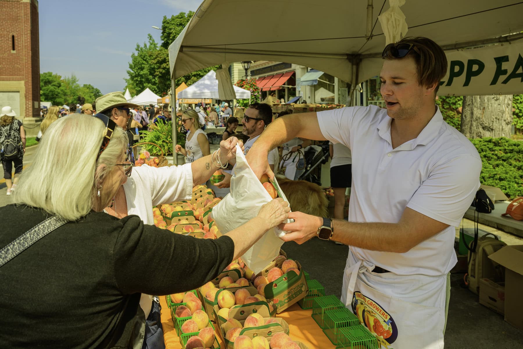 Over at Lepp Farms' fruit stand, Alex Ruddy helps a happy customer add some peaches to her shopping bag.