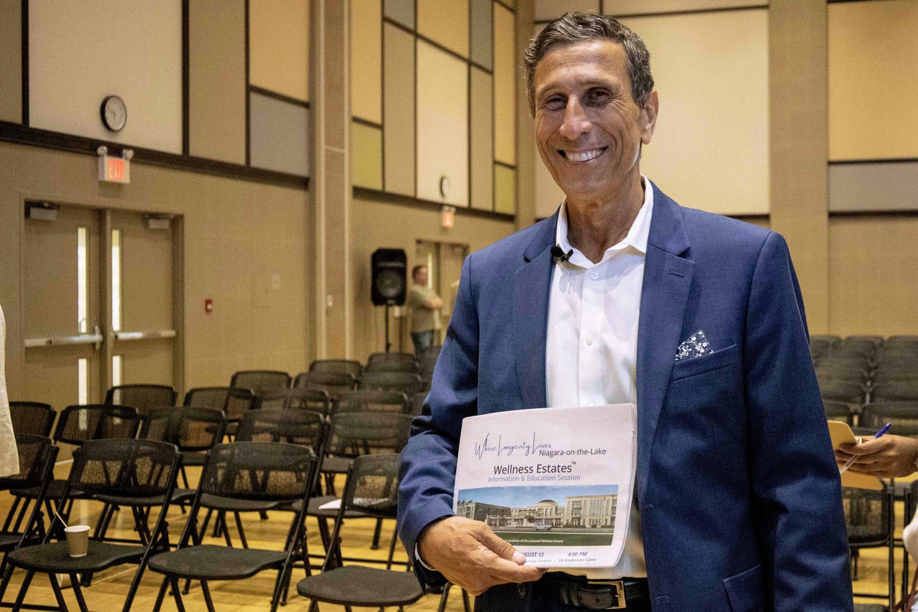 Dr. Nick Vaccaro stands with a Wellness Estates advertisement following his presentation at the NOTL Community Centre on Aug. 14.