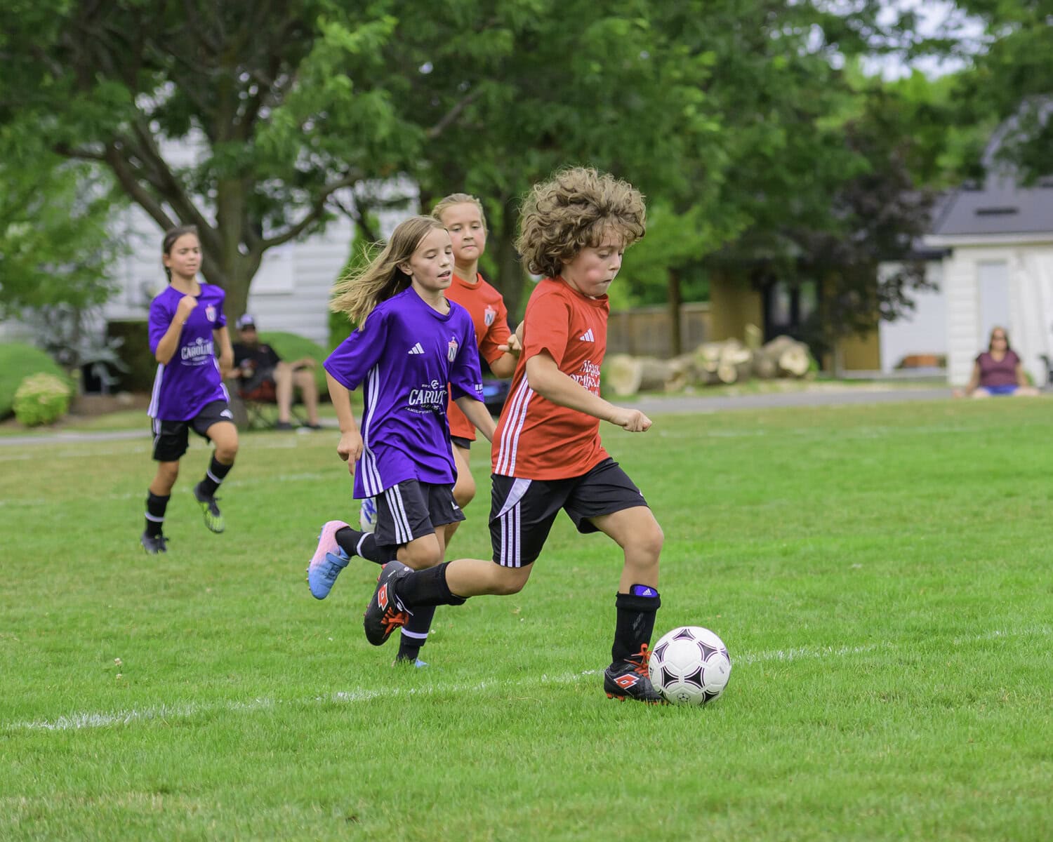 Playing in the U-9/U-10 league, Nick Conte from the Niagara-on-the-Lake Realty team gets the balls and goes running down the field, with players from the Caroline Cellars team running to catch up.