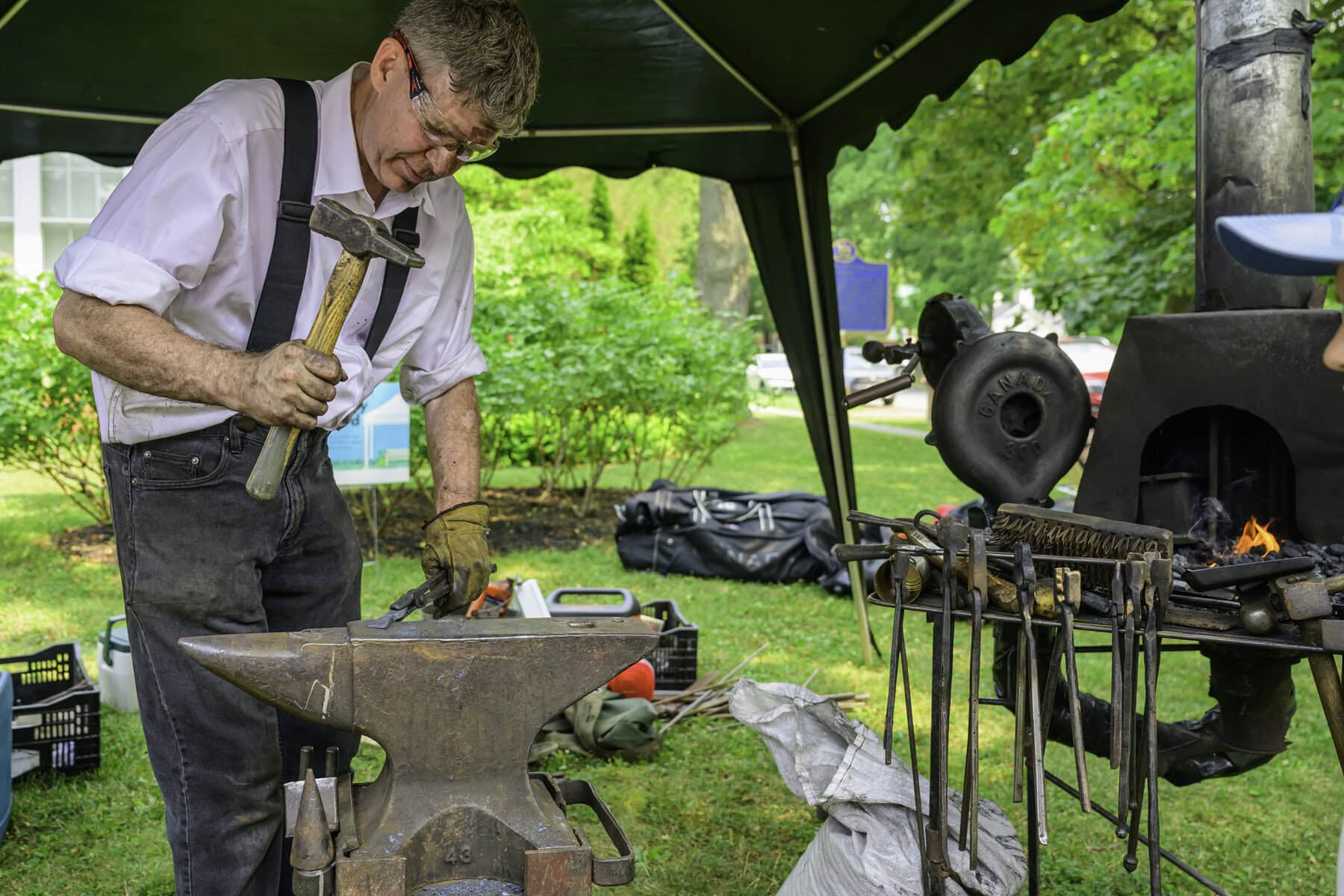 Blacksmith David Brandow hard at work, hammering a piece of metal against his anvil.