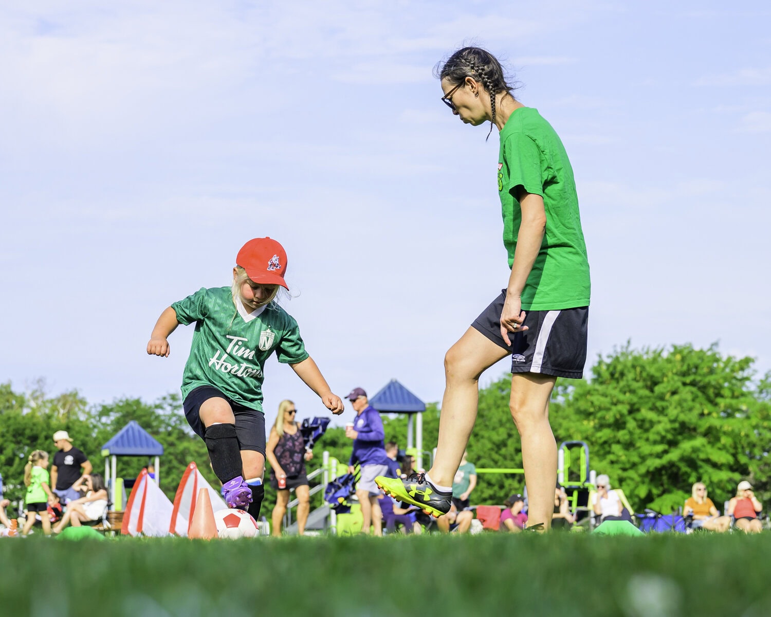Coach Rachel Goerz gives four-year-old Lake Van de Laar some pointers while running drills on the field.
