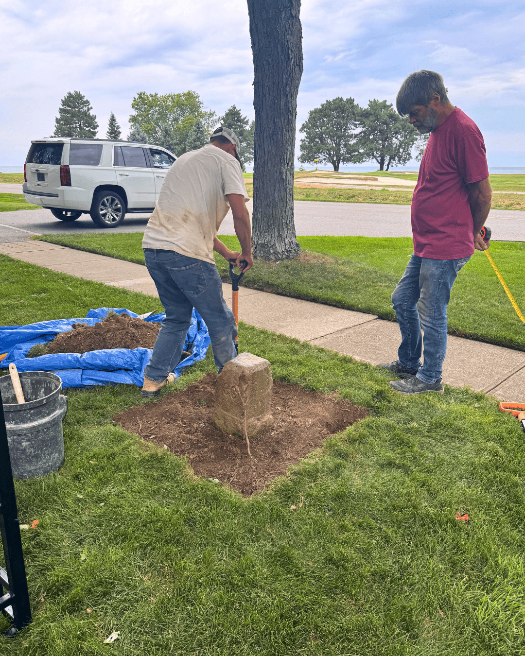 Workers handle a boundary stone during restoration.