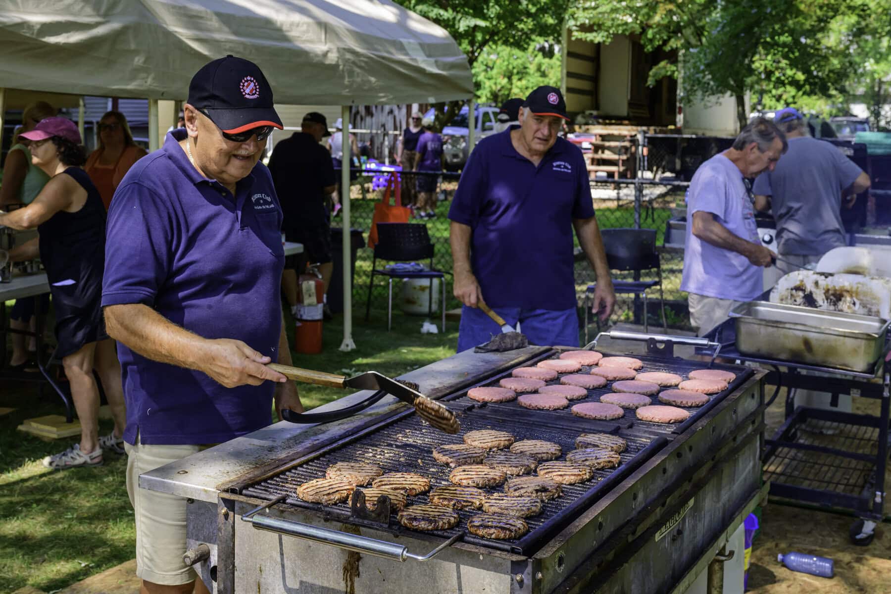 Willy Janzen and Rick Pozzebon cook up hamburgers for the hungry crowd of car enthusiasts.