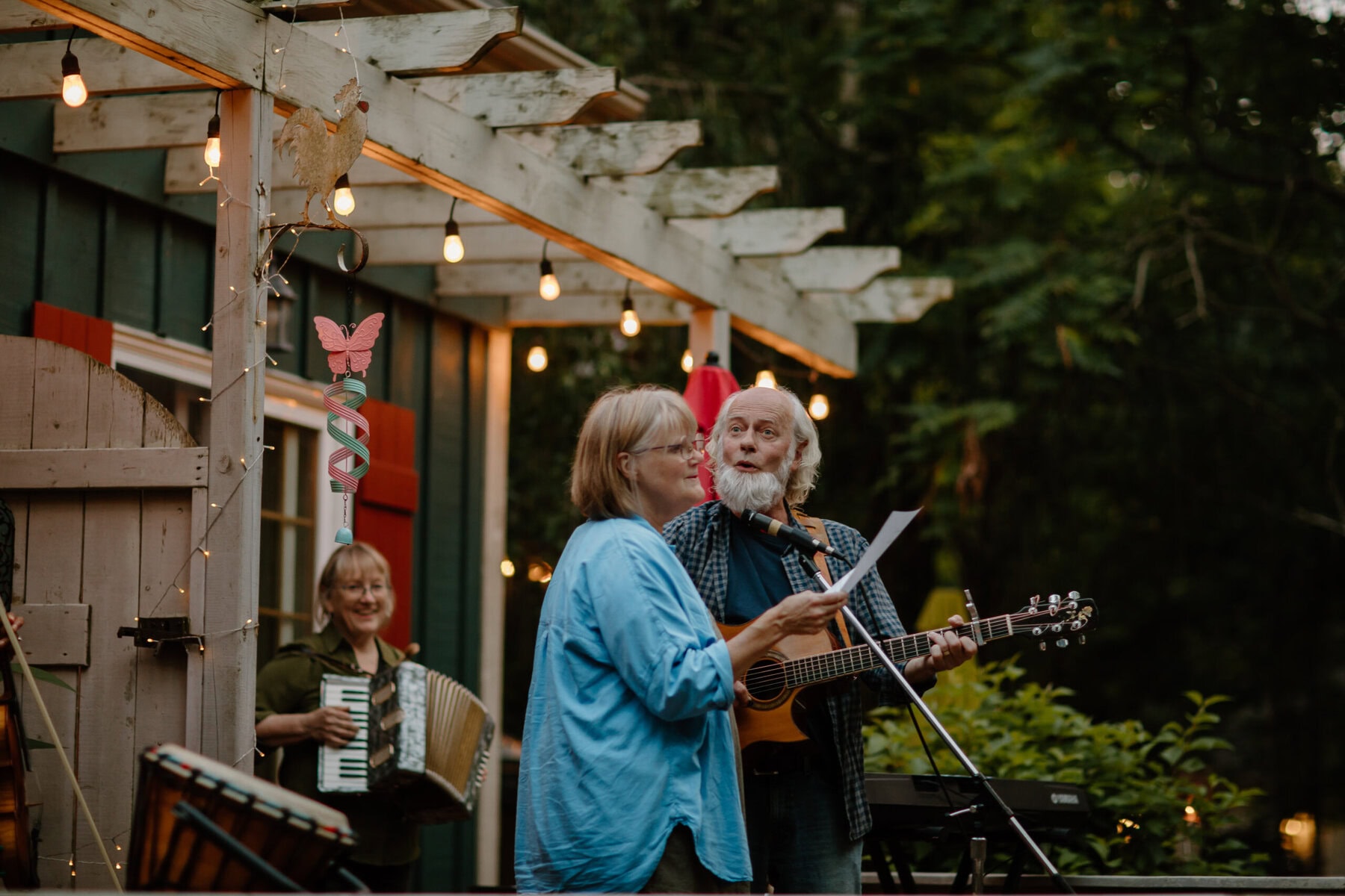 Colleen Wilder sings along with Brian Andres, who's playing acoustic guitar, and Jane Andres, seen in the background on the accordion.