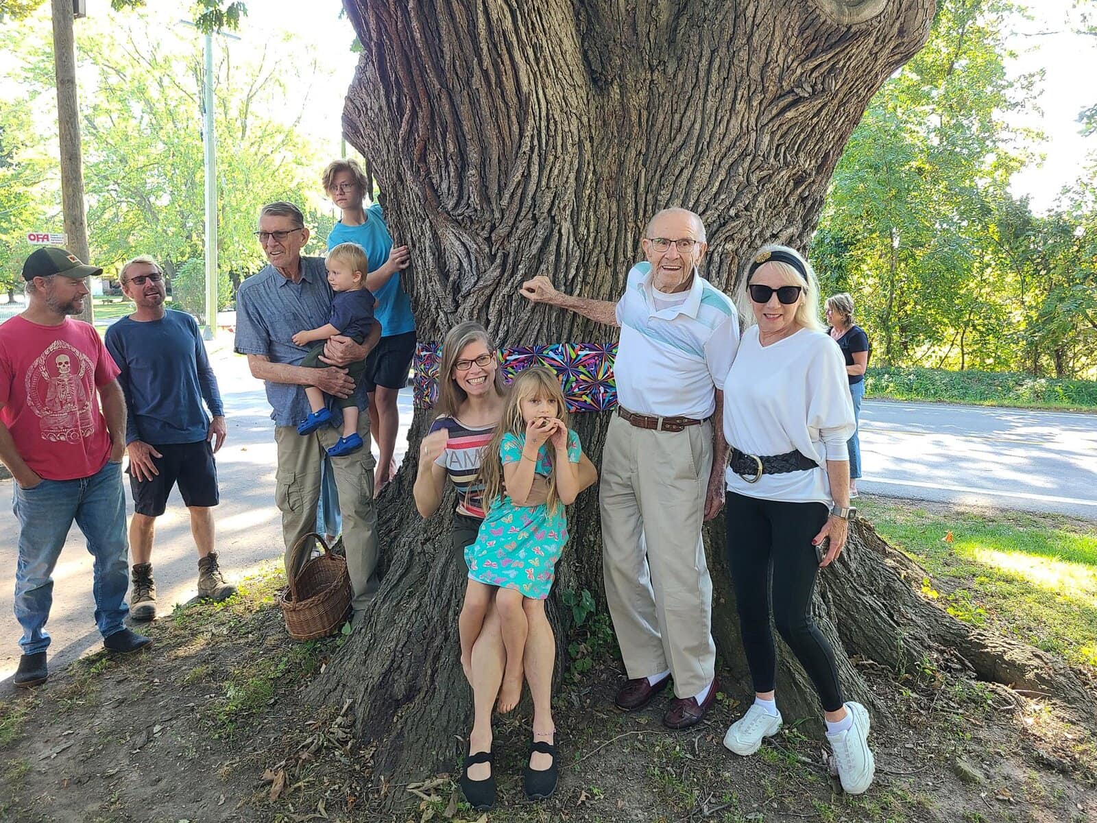 Andrew Epp, Scott Epp, Dan Epp, Liam Epp (held by Dan), Wren Epp-McGinnis, Jennifer Epp, Maeve Epp-McGinnis, Abe Epp and Idy Epp  stand beside the centuries-old oak they protected for decades on their Lakeshore Road farm. 