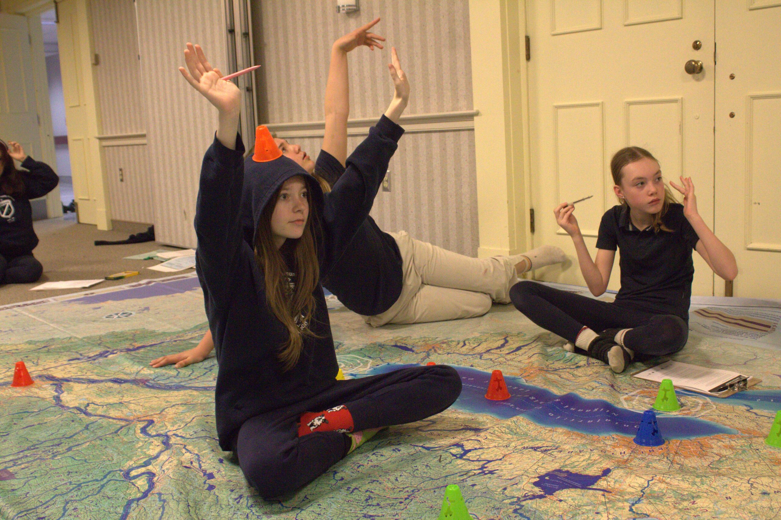 Zara Hamer, with a cone on her head, has a little fun beside Amelia Walton while engaging with Biinaagami map provided by Canadian Geographic to Royal Oak School on Tuesday.