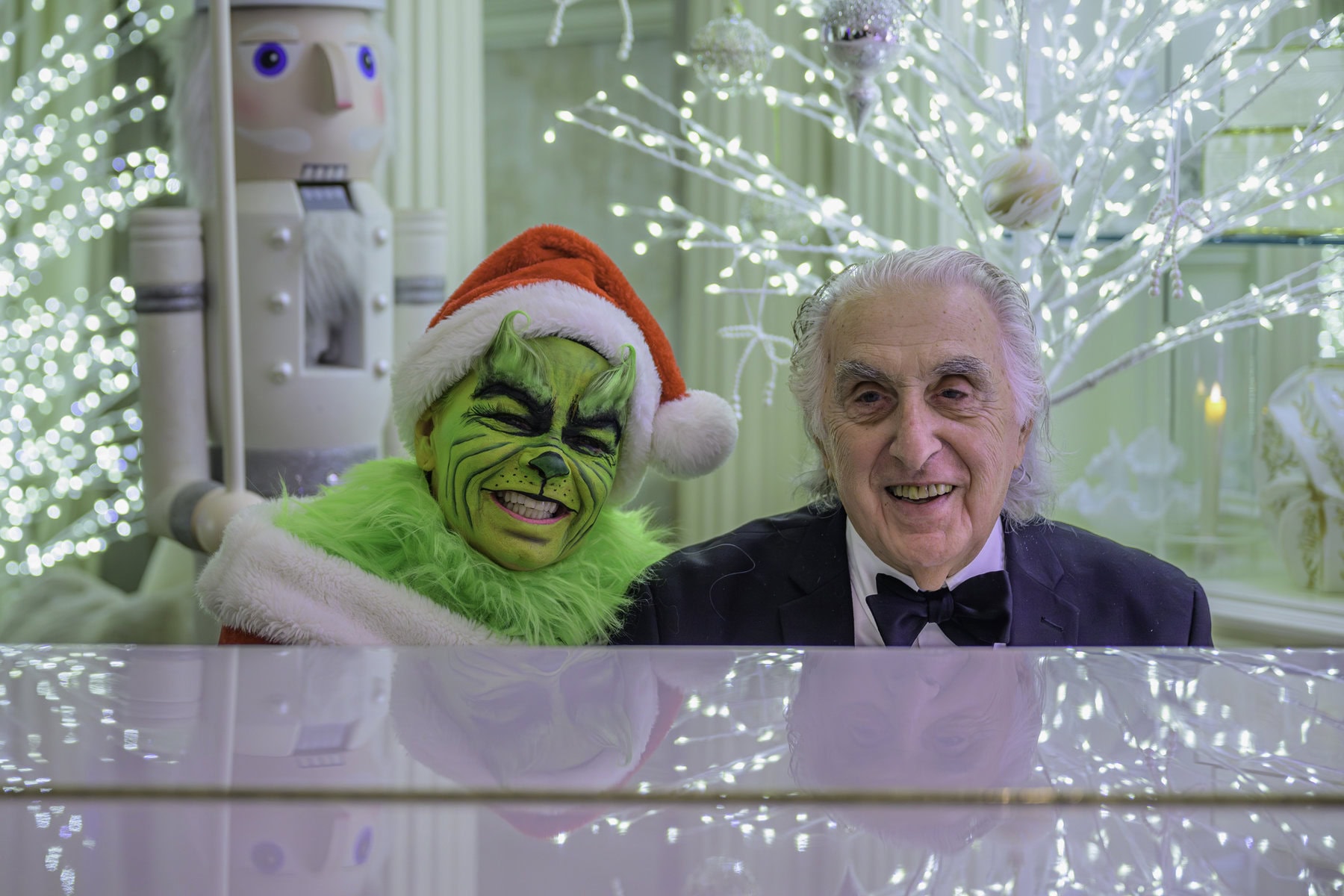 Tina Lu, dressed as the not-so-mean Grinch, alongside Eddy Pizza at the McArthur Estate's grand piano.