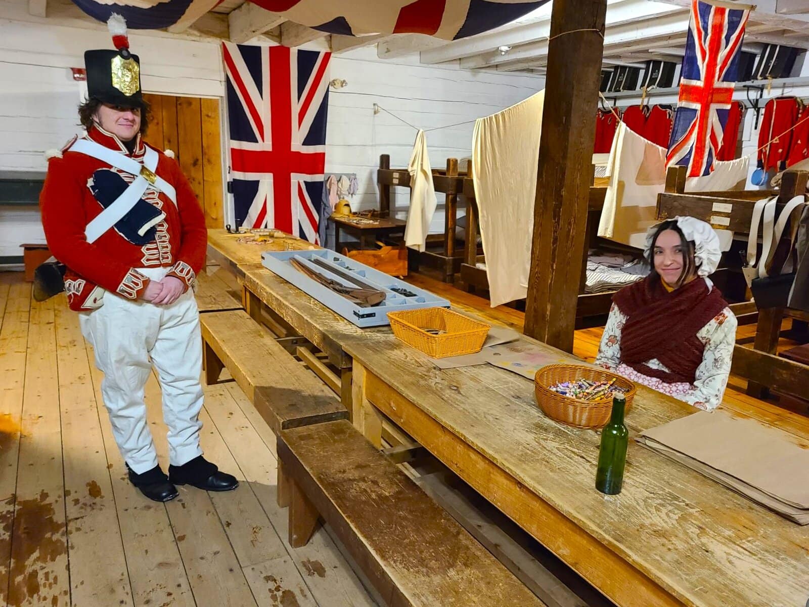 Sam Challen stands in the barracks of Blockhouse Two with Paloma Wapinski-Webb, hosting hands-on craft activities for visitors. 