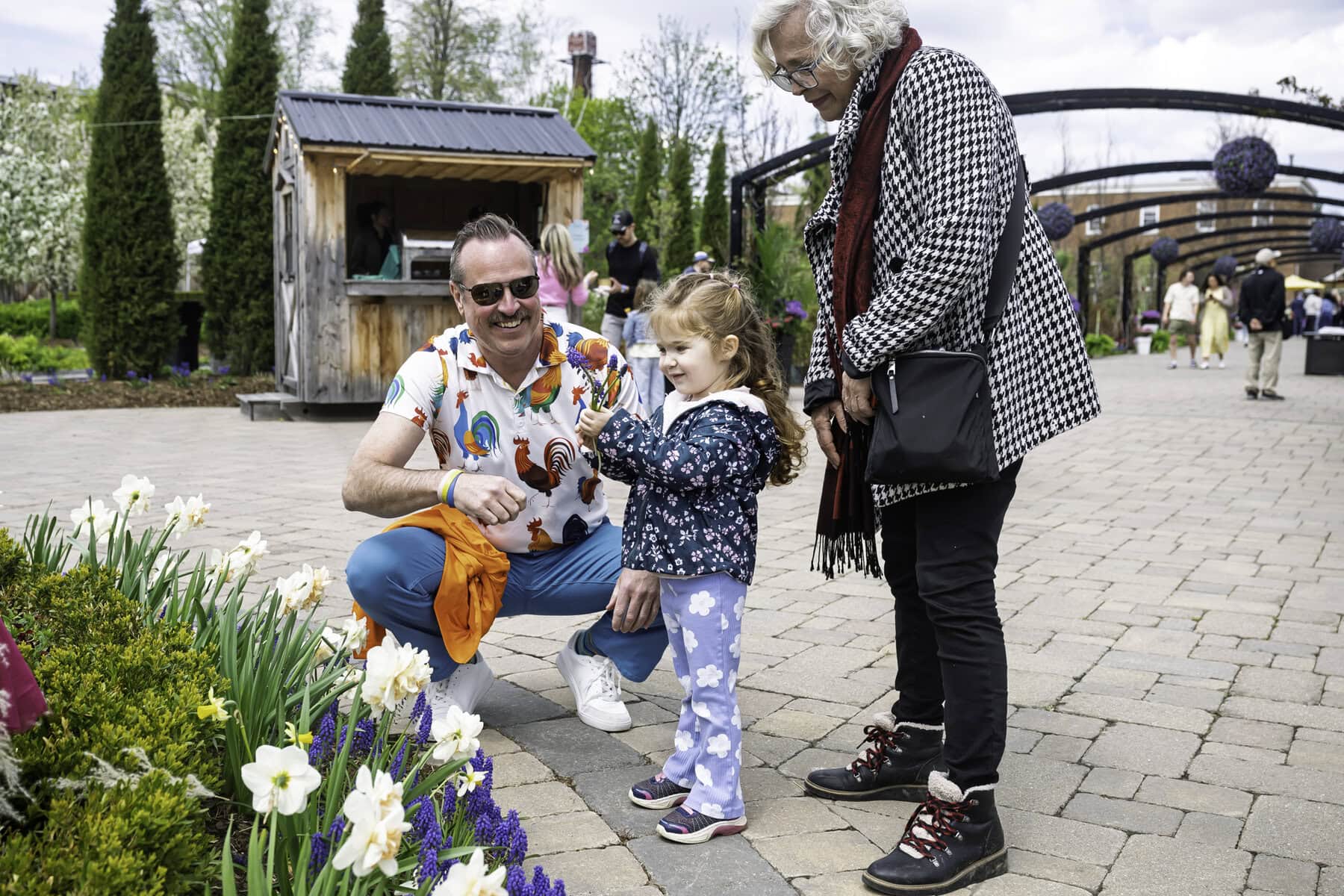 Flowers, like all great things in life, are made for sharing: Jamie Drummond, general manager of the Pillar and Post, gifts three-year-old Ave Teague, accompanied by Farrah Kamsei, a few flowers from the display at the hotel.