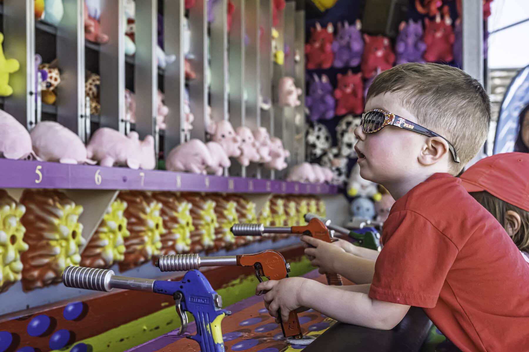 Three-year-old Theo Carr tries his hand at the water gun game, aiming for a bullseye.