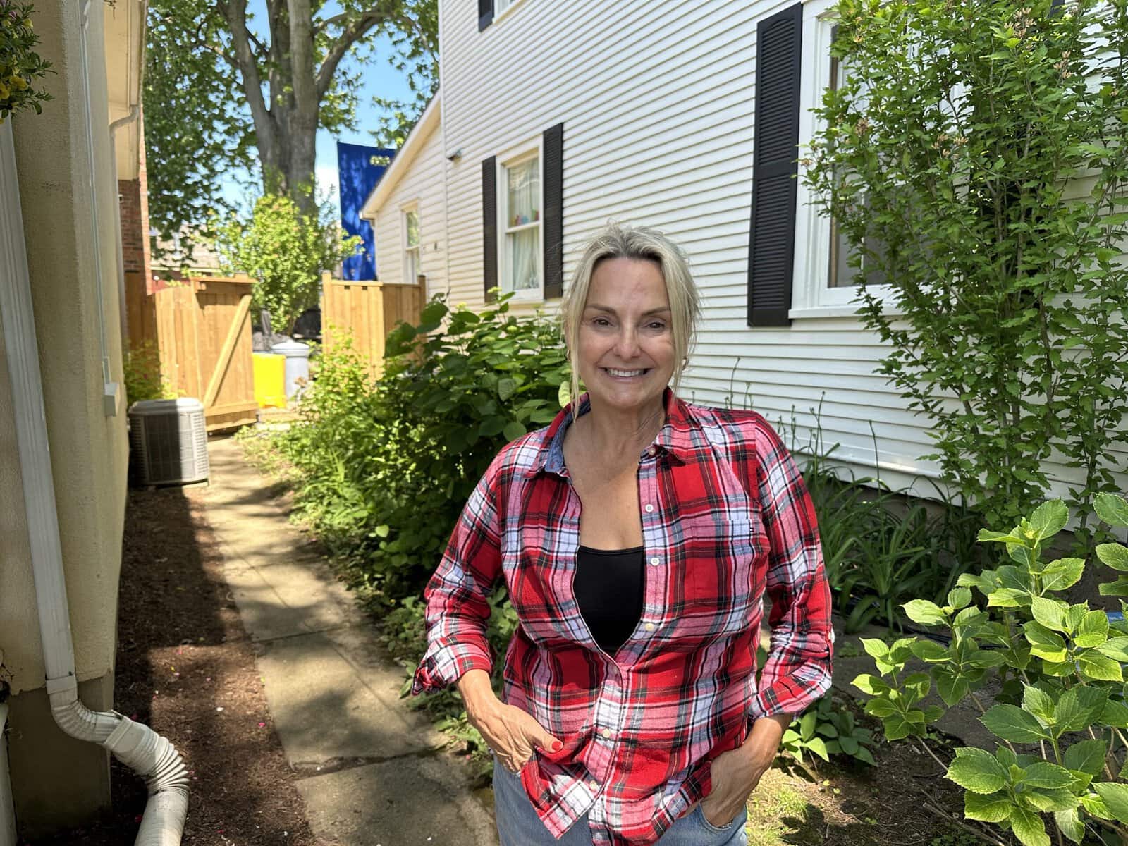 Melanie Farquhar stands beside her Johnson Street home, where support equipment for the filming of the Hollywood adaptation of “Beach Read,” including the blue screen visible in the background, has become part of the view outside her door.