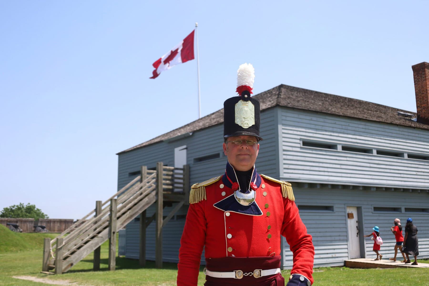 Fort George managing supervisor Dan Laroche stands in uniform beneath the Canadian flag during Canada Day celebrations at the national historic site.