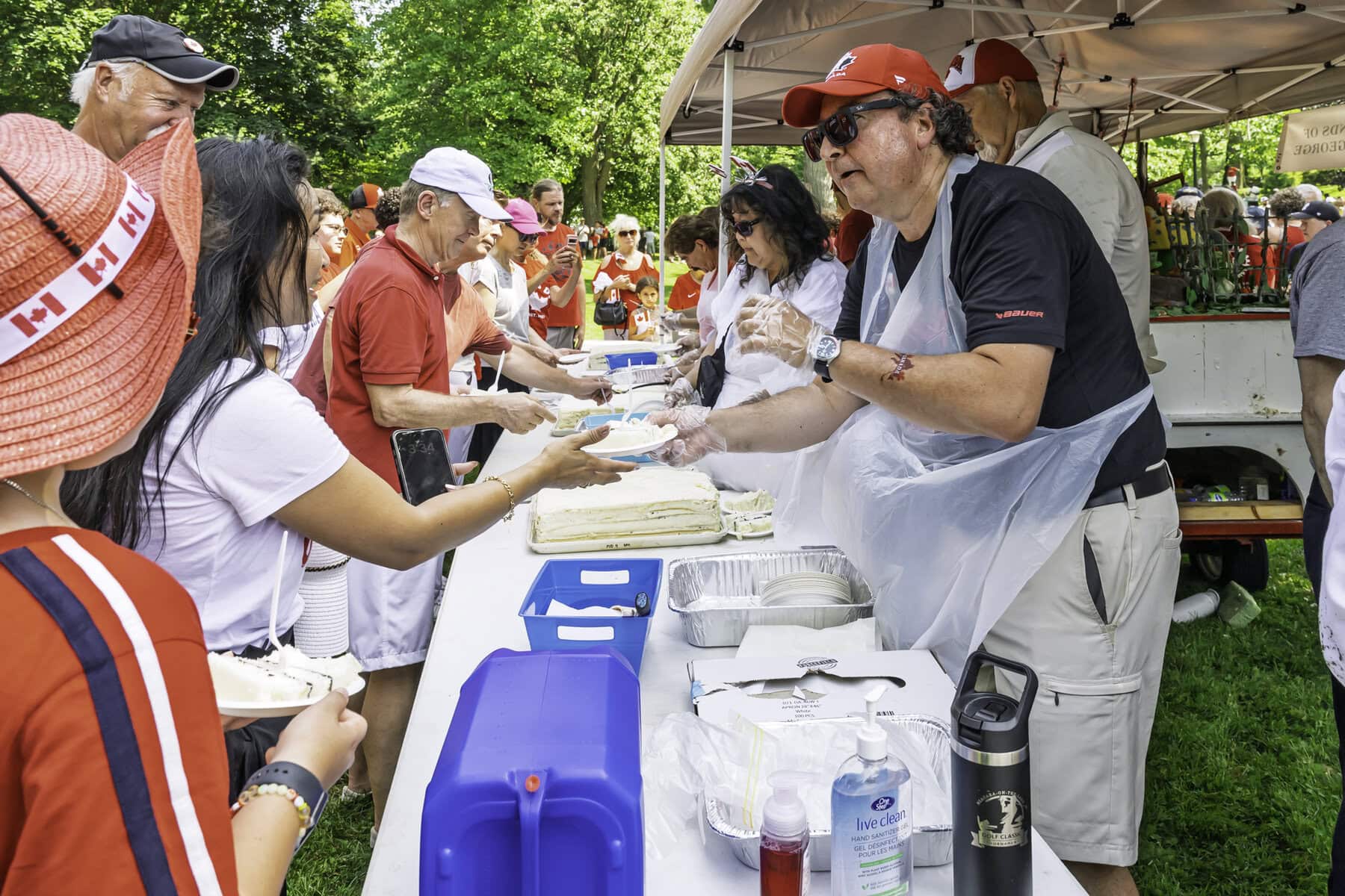 Lord Mayor Gary Zalepa doles out slices of cake to a crowd of hungry people at Simcoe Park in sweltering heat.