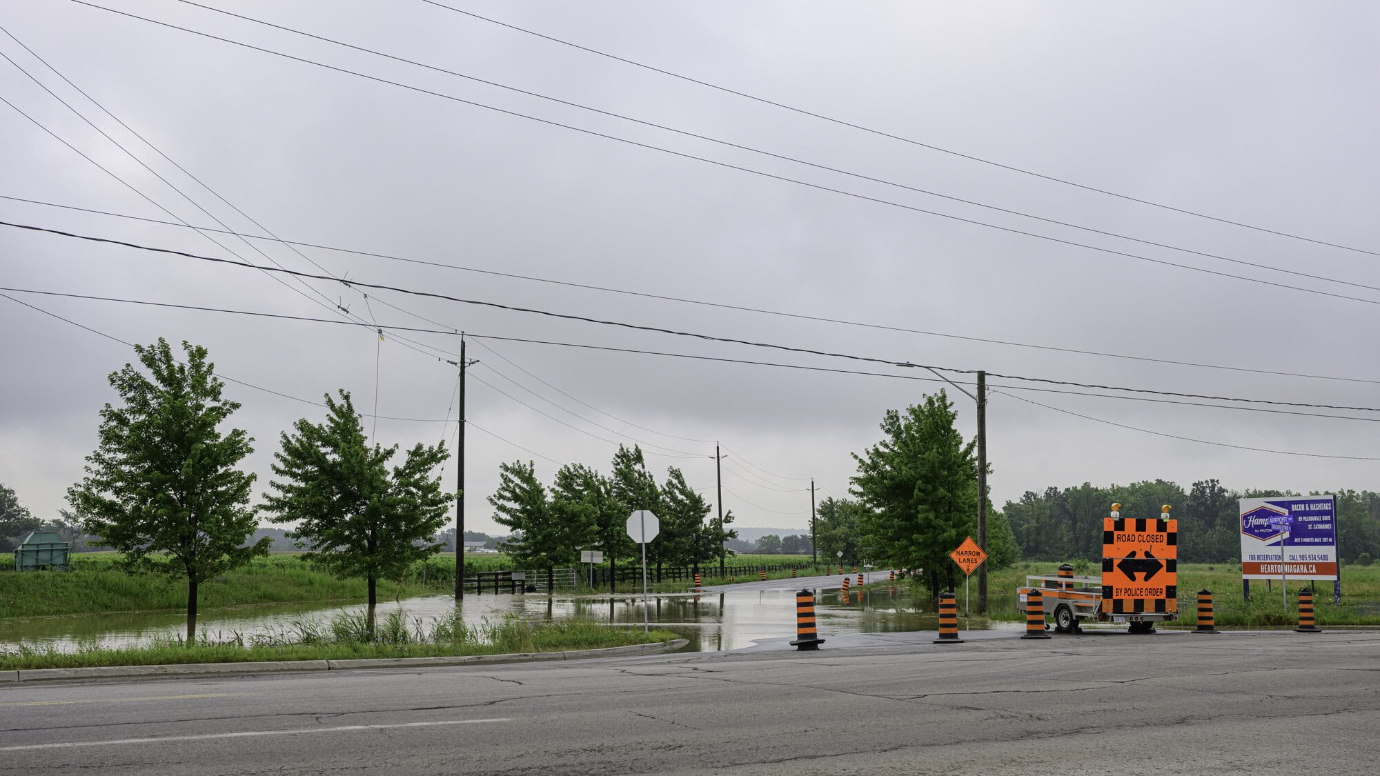 The entrance to Airport Road at Niagara Stone Road is closed to traffic, with the road heavily flooded, along with the adjacent Queenston Road.