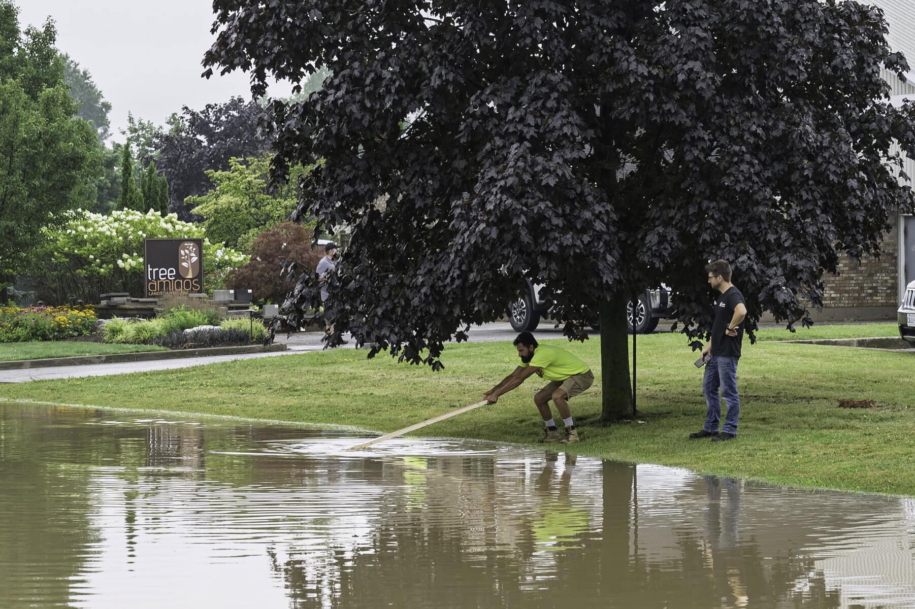 Over on Henegan Road, Phil Hering tries to clear the catch basin as the residential street is flooded.