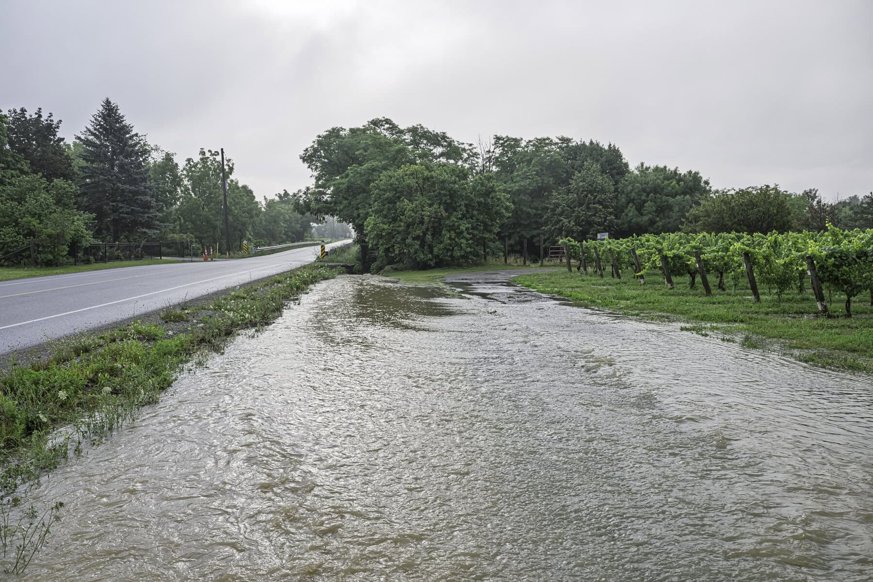 This stormwater ditch on Line 3 Road is at near-maximum capacity, with water rushing toward the connected reservoir nearby.