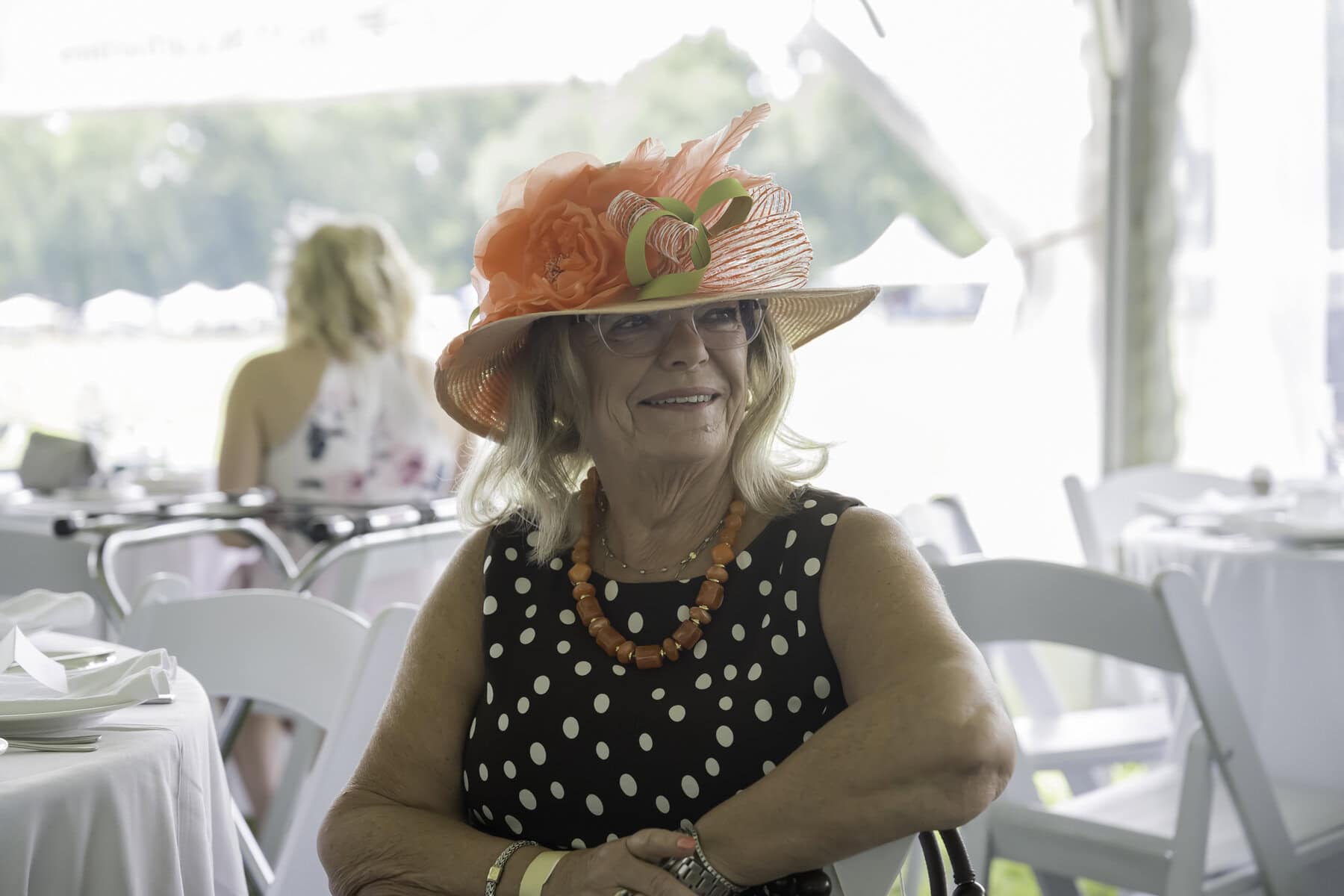 Vicki Craig's coral chapeau is a bright spot of joy. Many attendees came to the match donning fancy hats, a part of polo match tradition.