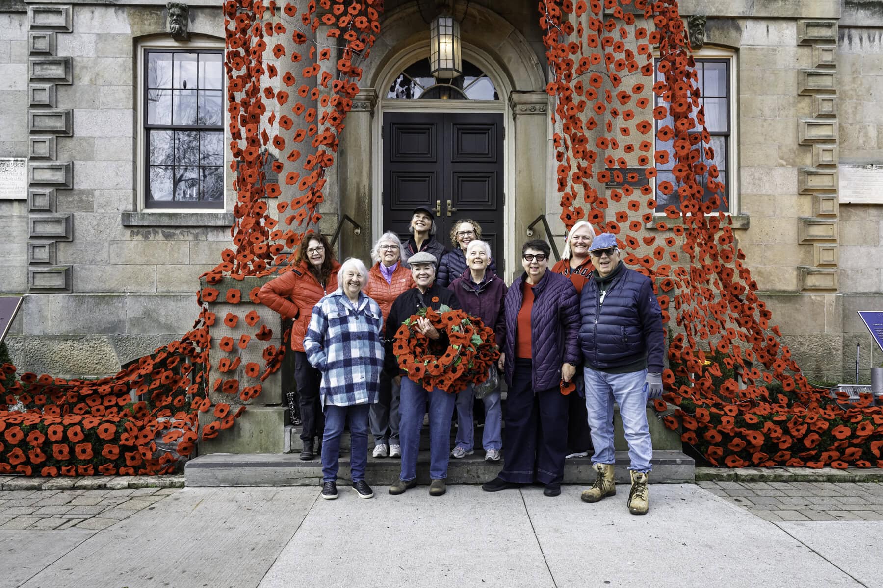 A few of the many volunteers who make the Poppy Project possible, after finishing their installation at the Old Court House on Monday.