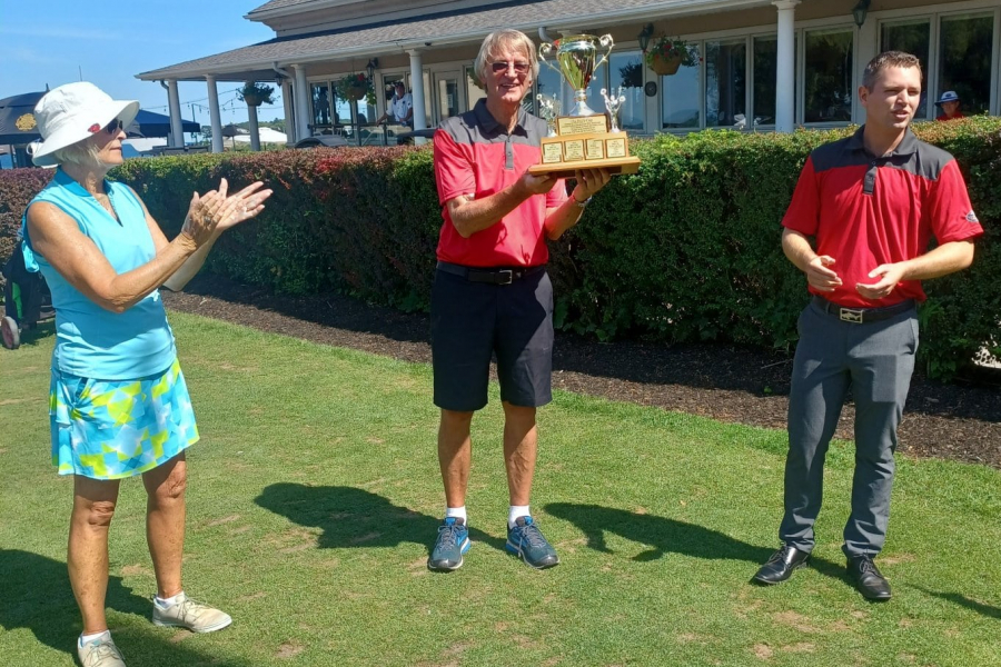 Harry Huizer hoists the Pro's Cup, while Martha Cruikshank and pro Keith Vant look on.