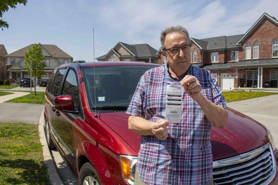 Niagara on the Green resident holds up a ticket he received for parking on his street last April. He approached town council on July 25, asking them to consider easing parking restrictions in the neighbourhood.