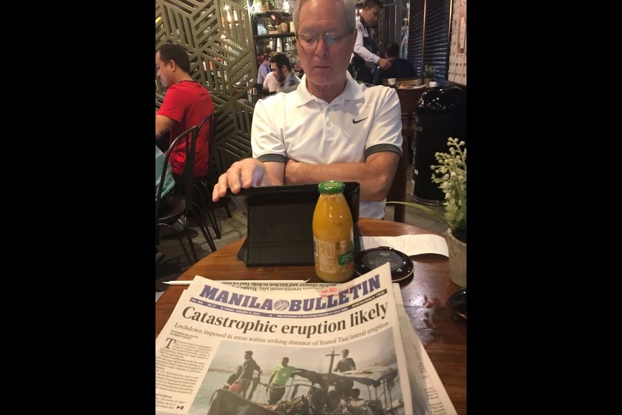 Volcano-Writer_Sharon_Fraynes_husband_Bill_French_checks_out_the_news_during_their_visit_to_Manila._Supplied_Sharon_Frayne.jpg